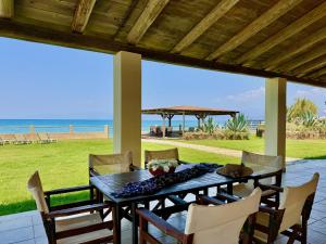 a table on a patio with a view of the beach at Beachfront Villa Calypso with private pool by DadoVillas in Acharavi