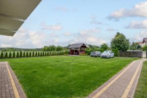 a grassy yard with a gazebo and two cars parked at Komfort i spokój blisko natury - Apartamenty i pokoje ARKO in Ostrowo
