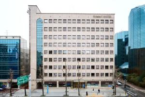 a large white building in a city with tall buildings at Summit Hotel Seoul Dongdaemun in Seoul