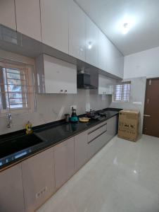 Elite Homes في تشكماغالور: مطبخ مع خزائن بيضاء وقمم منضدة سوداء