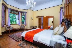 a bedroom with a large bed and a chandelier at Balrampur House Heritage Hotel in Nainital
