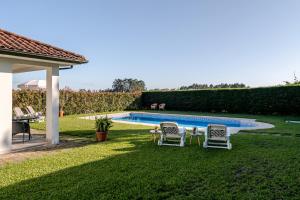a yard with two chairs and a swimming pool at Quinta do Outeirinho - Villa Deluxe in Celorico de Basto