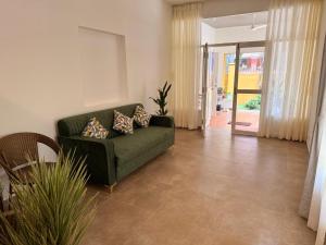a living room with a green couch with pillows on it at Hibiscus By Tara Suites in Jāmb +2 photos
