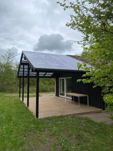 a black building with a bench on a wooden deck at Rosenby Hytten in Dronninglund