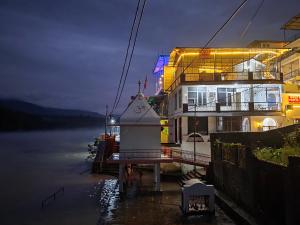 un bâtiment situé à côté d'une masse d'eau la nuit dans l'établissement hotel tripta ganga, à Rishikesh
