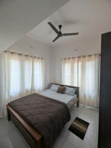 a bedroom with a bed and a ceiling fan at Elite Homes in Chikmagalūr