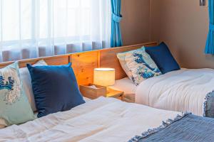 a bedroom with two beds with blue and white pillows at Third Place Tokyo - Aoto - in Tokyo