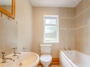 a bathroom with a toilet and a tub and a sink at 4 Bed in Harlech 89631 in Harlech