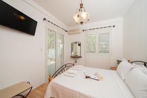 a white bedroom with a bed and a window at Coral Cottage House by A&D Properties in Porto Rafti