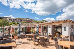 eine Terrasse mit Tischen, Stühlen und Sonnenschirmen in der Unterkunft Grimaud 4 personnes clim vue mer in Grimaud