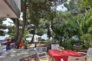a patio with a red table and chairs and trees at Villa A in Pirovac
