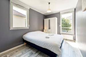 a small bedroom with a bed and two windows at La Terrasse in Woippy