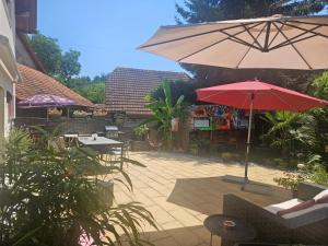a patio with tables and a red umbrella at Guesthouse Claudia in Leuzigen