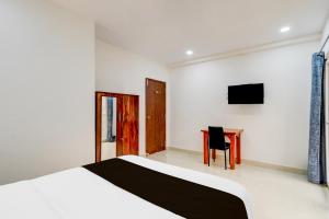 a bedroom with a bed and a desk and a television at Super Townhouse Nallagandla Nest in Hyderabad