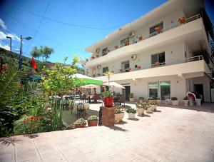 a large white building with plants and tables and chairs at Hotel Nika in Vlorë