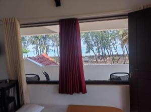a bedroom window with a view of the ocean at Relax inn cherai beach in Cochin