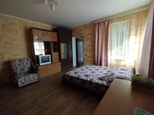 a bedroom with a bed and a chair and a television at Гостевой домик in Chornomorsk