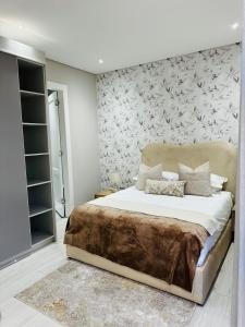 una camera con un grande letto e un muro di Acacia Villas Blue Hills - 3 Bedroom Luxury Villa a Midrand Altre 18 foto