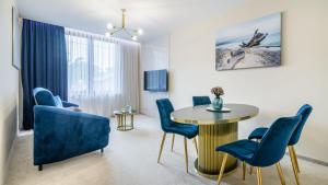 een woonkamer met een tafel en blauwe stoelen bij CONTINENTAL Apartamenty Piamola in Krynica Morska
