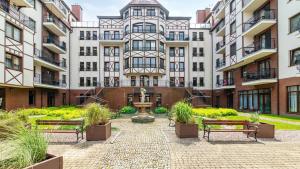 een binnenplaats met banken voor een gebouw bij CONTINENTAL Apartamenty Piamola in Krynica Morska