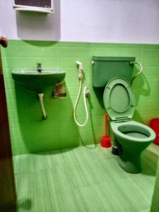 a green bathroom with a toilet and a sink at Farah Homestay in Varkala