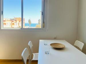 a table with chairs and a white table and a window at Apartamento Romanilla Roquetas in Roquetas de Mar