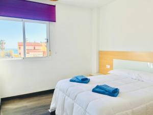 a bedroom with a bed with two blue towels on it at Apartamento Romanilla Roquetas in Roquetas de Mar