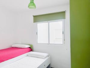 a bedroom with a pink bed and a window at Apartamento Romanilla Roquetas in Roquetas de Mar