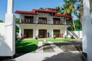 a white house with a balcony and a yard at Jasmine Villa in Bentota