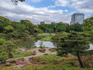 a park with a pond and trees and a city at Sakura Fan 2F in Tokyo