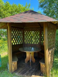 a wooden gazebo with a table and benches at Вілла ЮРАН Східниця in Skhidnitsa