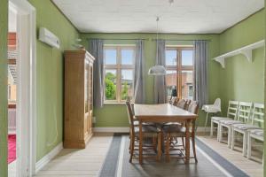 a dining room with green walls and a table and chairs at Holiday Home With Billiards, Garden, Great Spot in Grenå