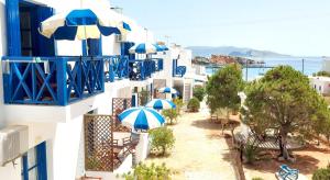a balcony with blue and white buildings with umbrellas at Aegean Star Hotel in Karavostasi
