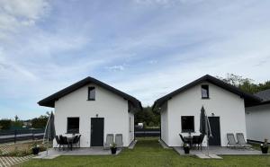 two white buildings with tables and chairs in a yard at Domki M&M in Kołczewo