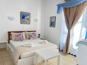 a white bedroom with a bed and a window at Aegean Star Hotel in Karavostasi
