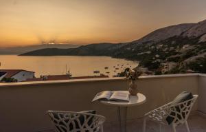 a table and chairs on a balcony with a view of the water at Eola Leisure Rooms in Stara Baška