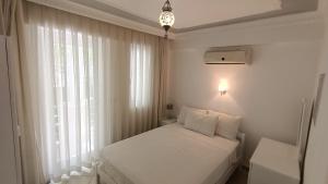 een witte slaapkamer met een bed en een raam bij Baba View Apart in Fethiye