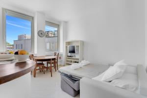 una stanza bianca con un letto e una sala da pranzo con un tavolo di Navigli - Porta Ticinese - Luminoso monolocale a Milano