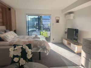a bedroom with a bed and a tv and a balcony at Cozy 1 BR 1 Bathroom studio in Christchurch