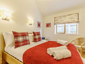 une chambre avec un grand lit avec une couverture rouge dans l'établissement 3 Bed in Blakeney 83628, à Blakeney