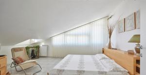 1 dormitorio blanco con 1 cama y 1 silla en Villa Sissi, en Cava dʼAliga