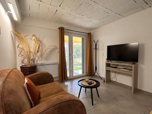 a living room with a couch and a flat screen tv at Nice App Private Parking, Garden, Furnished Terrace in Châteauneuf-du-Rhône