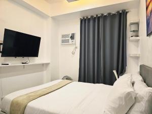 a hotel room with a bed and a television at Modern Cozy Studio in Dasmariñas