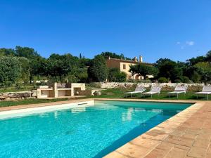 a swimming pool with chairs and a house in the background at Il Paglieto - Natura, Stelle, Relax e Piscina in Manciano