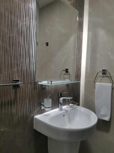 a bathroom with a white sink and a mirror at Saray Musheireb Hotel Suites and Apartment in Doha
