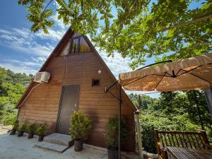 un petit bâtiment en bois avec une porte et un parapluie dans l'établissement Cozy Cottage In Makhindjauri with Forest and Sea Views, à Makhinjauri