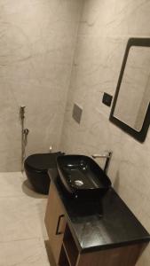 a bathroom with a black toilet and a sink at LA VILLA VYTHIRI Resort in Vythiri +8 photos