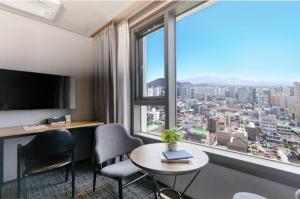 Habitación de hotel con mesa, sillas y ventana grande. en With Stay Jeju Hotel, en Jeju