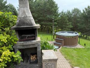 a stone fireplace with a hot tub in a garden at Sodyba Vilagio in Alanta