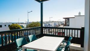 Una mesa blanca y sillas en un balcón con vista. en Blancazul El Marisco, en Playa Blanca